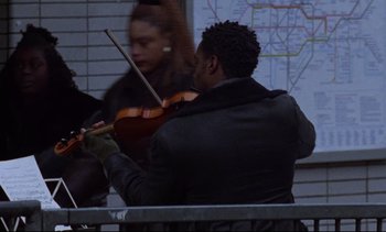 Movie still from “Nil by Mouth” (1997), directed by Gary Oldman – A man playing a violin in front of a woman; Medium shot, Low angle