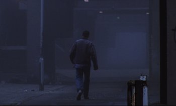 Movie still from “Nil by Mouth” (1997), directed by Gary Oldman – A man walking down a street in the fog; Wide shot, Low angle