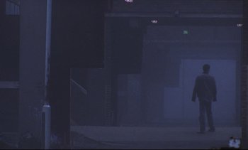 Movie still from “Nil by Mouth” (1997), directed by Gary Oldman – A person riding a skate board on a foggy day; Extreme Wide shot, Low angle