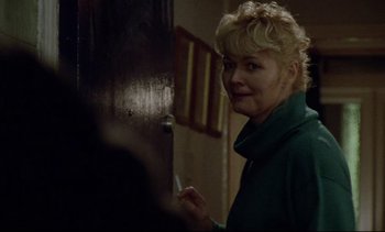Movie still from “Nil by Mouth” (1997), directed by Gary Oldman – A woman standing in front of an open door; Close Up shot, Over the shoulder angle