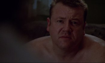 Movie still from “Nil by Mouth” (1997), directed by Gary Oldman – A person sitting in a room; Close Up shot, Over the shoulder angle