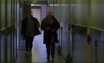 Movie still from “Nil by Mouth” (1997), directed by Gary Oldman – Two women are walking down the hallway of a building; Wide shot, Low angle