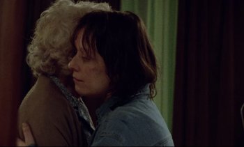 Movie still from “Nil by Mouth” (1997), directed by Gary Oldman – A woman is hugging another woman in a room with green curtains; Close Up shot, Over the shoulder angle
