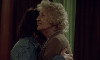 Movie still from “Nil by Mouth” (1997), directed by Gary Oldman – An older woman hugging a younger woman in a room; Medium shot, Over the shoulder angle