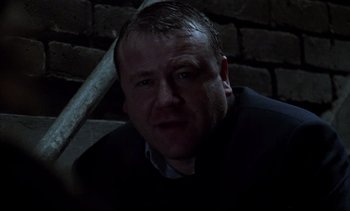 Movie still from “Nil by Mouth” (1997), directed by Gary Oldman – A person sitting in a dark room; Close Up shot, Low angle
