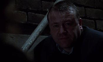 Movie still from “Nil by Mouth” (1997), directed by Gary Oldman – A person sitting in a dark room; Close Up shot, Low angle