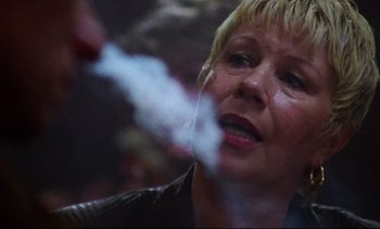 Movie still from “Nil by Mouth” (1997), directed by Gary Oldman – An older woman is smoking a cigarette in front of a mirror; Close Up shot, Low angle