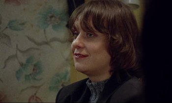 Movie still from “Nil by Mouth” (1997), directed by Gary Oldman – A woman with brown hair wearing a black jacket; Close Up shot, Over the shoulder angle