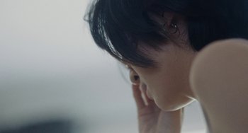 Movie still from “Nimic” (2019), directed by Yorgos Lanthimos – A person with their ear buds in their ears; Extreme Close Up shot, Over the shoulder angle