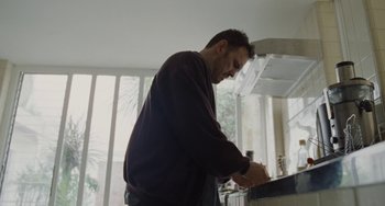 Movie still from “Nimic” (2019), directed by Yorgos Lanthimos – A man standing at a counter in a kitchen; Medium shot, Low angle