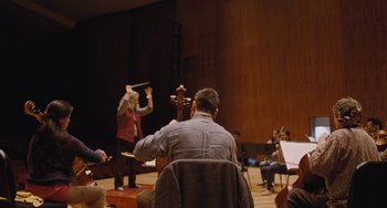 Movie still from “Nimic” (2019), directed by Yorgos Lanthimos – A man sitting in front of an orchestra playing; Extreme Wide shot, Low angle