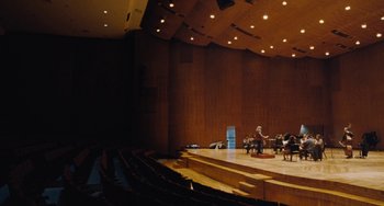 Movie still from “Nimic” (2019), directed by Yorgos Lanthimos – A group of people sitting on a stage in an auditorium; Extreme Wide shot, High angle