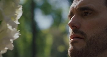 Movie still from “Nimic” (2019), directed by Yorgos Lanthimos – A man's face with trees in the background; Extreme Close Up shot, Low angle