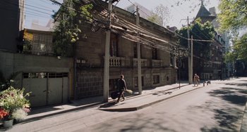 Movie still from “Nimic” (2019), directed by Yorgos Lanthimos – A man riding a bike down a street next to a building; Extreme Wide shot, High angle
