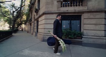 Movie still from “Nimic” (2019), directed by Yorgos Lanthimos – A man walking down the street holding a bag of flowers; Wide shot, High angle