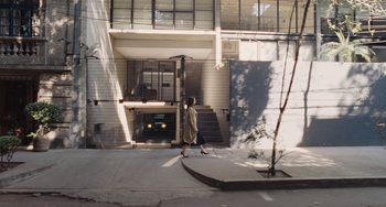 Movie still from “Nimic” (2019), directed by Yorgos Lanthimos – A woman walking down the sidewalk in front of a building; Extreme Wide shot, High angle