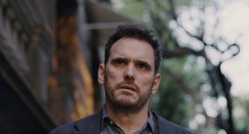 Movie still from “Nimic” (2019), directed by Yorgos Lanthimos – A person wearing a suit and tie; Close Up shot, Over the shoulder angle