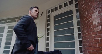 Movie still from “Nimic” (2019), directed by Yorgos Lanthimos – A man walking in front of an open door; Medium shot, Low angle