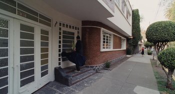 Movie still from “Nimic” (2019), directed by Yorgos Lanthimos – A person walking down the steps of a brick building; Extreme Wide shot, High angle