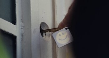 Movie still from “Nimic” (2019), directed by Yorgos Lanthimos – A hand holding a key with a smiley face on it; Extreme Close Up shot, High angle