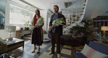Movie still from “Nimic” (2019), directed by Yorgos Lanthimos – A man and a woman standing next to each other holding flowers; Wide shot, Low angle
