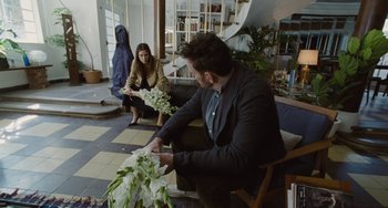 Movie still from “Nimic” (2019), directed by Yorgos Lanthimos – A man sitting in front of a woman holding flowers; Medium shot, Over the shoulder angle
