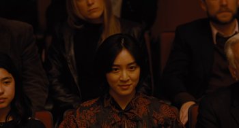 Movie still from “Nimic” (2019), directed by Yorgos Lanthimos – A woman sitting in front of a group of other people; Medium shot, Over the shoulder angle