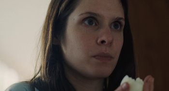 Movie still from “Nimic” (2019), directed by Yorgos Lanthimos – A person holding a piece of food; Close Up shot, Low angle