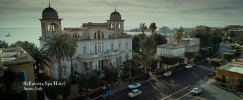 Movie still from “Nine” (2009), directed by Rob Marshall – An aerial view of a large white building with palm trees in front of it; Extreme Wide shot, Low angle