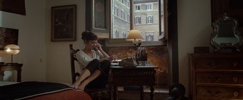 Movie still from “Nine” (2009), directed by Rob Marshall – A woman sitting at a table in front of a window; Wide shot, High angle