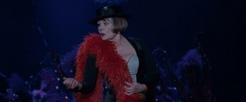 Movie still from “Nine” (2009), directed by Rob Marshall – A woman wearing a hat and a red boa; Medium shot, Over the shoulder angle
