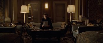 Movie still from “Nine” (2009), directed by Rob Marshall – A person sitting on a couch in a living room; Wide shot, Over the shoulder angle