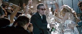 Movie still from “Nine” (2009), directed by Rob Marshall – A man in a suit and tie surrounded by people; Medium shot, Over the shoulder angle