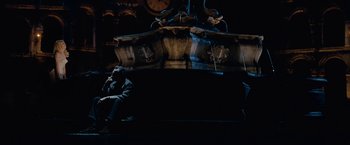 Movie still from “Nine” (2009), directed by Rob Marshall – A man sitting on a bench next to a clock tower at night; Wide shot, High angle