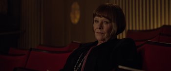 Movie still from “Nine” (2009), directed by Rob Marshall – An older woman sitting on a red couch; Close Up shot, Low angle