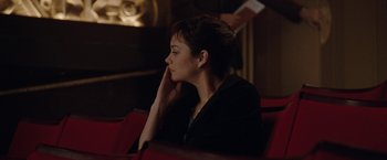 Movie still from “Nine” (2009), directed by Rob Marshall – A woman sitting in a red chair with her head resting on her hand; Medium shot, High angle