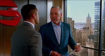 Movie still from “Nine Lives” (2016), directed by Barry Sonnenfeld – Two men in suits talking in front of a large window; Medium shot, Over the shoulder angle