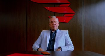 Movie still from “Nine Lives” (2016), directed by Barry Sonnenfeld – An older man sitting at a table in front of a wall; Medium shot, Over the shoulder angle