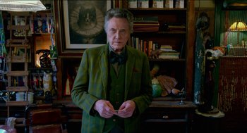 Movie still from “Nine Lives” (2016), directed by Barry Sonnenfeld – An older man in a green suit standing in front of a book case; Medium shot, Low angle