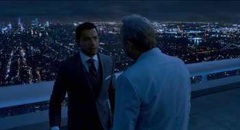 Movie still from “Nine Lives” (2016), directed by Barry Sonnenfeld – Two men in suits are standing next to each other in front of a city skyline at night; Medium shot, Over the shoulder angle
