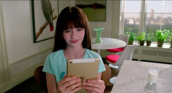 Movie still from “Nine Lives” (2016), directed by Barry Sonnenfeld – A young girl holding an ipad while sitting at a table; Close Up shot, High angle