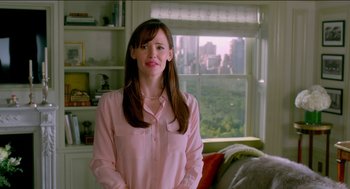 Movie still from “Nine Lives” (2016), directed by Barry Sonnenfeld – A woman in a pink shirt standing in front of a window; Medium shot, Over the shoulder angle