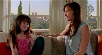 Movie still from “Nine Lives” (2016), directed by Barry Sonnenfeld – A woman sitting on a couch next to a little girl; Medium shot, Over the shoulder angle