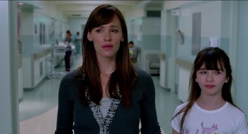 Movie still from “Nine Lives” (2016), directed by Barry Sonnenfeld – A woman standing in a hospital hallway looking sad; Close Up shot, Over the shoulder angle