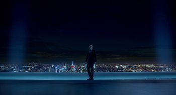 Movie still from “Nine Lives” (2016), directed by Barry Sonnenfeld – A man in a suit standing on a ledge in front of a city skyline at night; Extreme Wide shot, Low angle