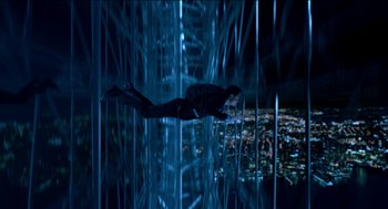 Movie still from “Nine Lives” (2016), directed by Barry Sonnenfeld – A man in a black suit is flying through the air in front of a city; Wide shot, Overhead angle
