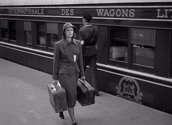 Movie still from “Ninotchka” (1939), directed by Ernst Lubitsch – A woman walking down a train platform carrying two suitcases; Wide shot, Low angle