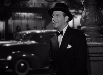 Movie still from “Ninotchka” (1939), directed by Ernst Lubitsch – A black and white photo of a man in a suit and hat; Medium shot, Low angle