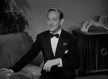 Movie still from “Ninotchka” (1939), directed by Ernst Lubitsch – A man in a tuxedo sitting on a couch; Medium shot, High angle