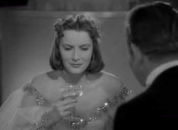 Movie still from “Ninotchka” (1939), directed by Ernst Lubitsch – A black and white photo of a woman holding a wine glass; Close Up shot, Over the shoulder angle